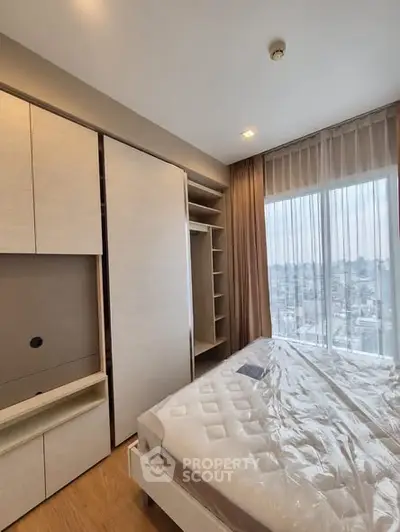 Modern bedroom with large window and built-in wardrobe offering city views.