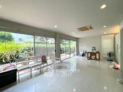 Spacious living room with large windows and garden view, perfect for relaxation and entertaining.