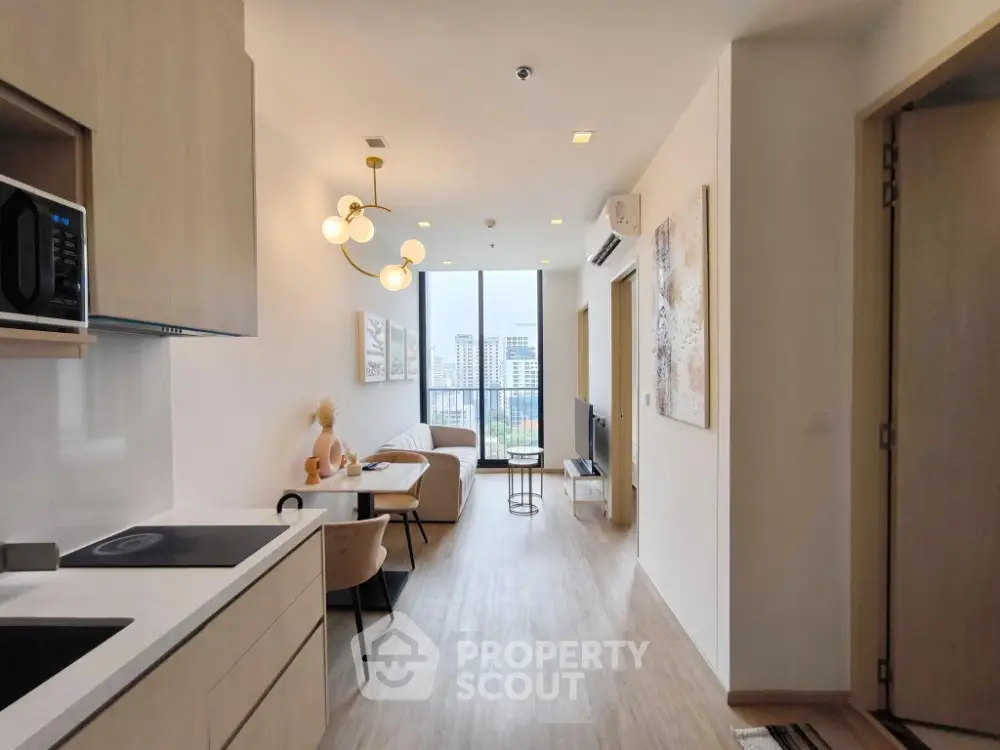 Modern open-plan living room with kitchen, stylish decor, and city view from balcony.