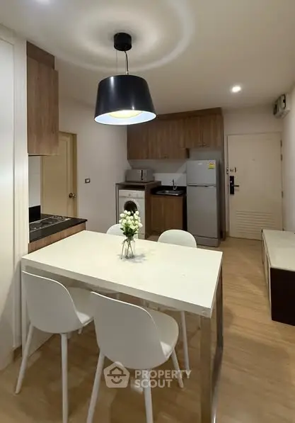 Modern kitchen with dining area, featuring sleek appliances and stylish lighting.
