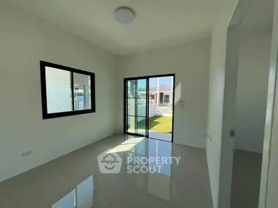 Bright empty room with large window and glossy floor tiles, overlooking a garden view.