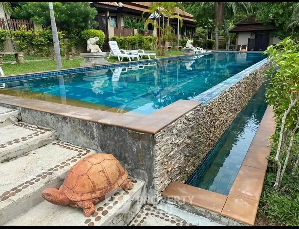 Luxurious outdoor pool area with serene garden and elegant stonework, perfect for relaxation and leisure.