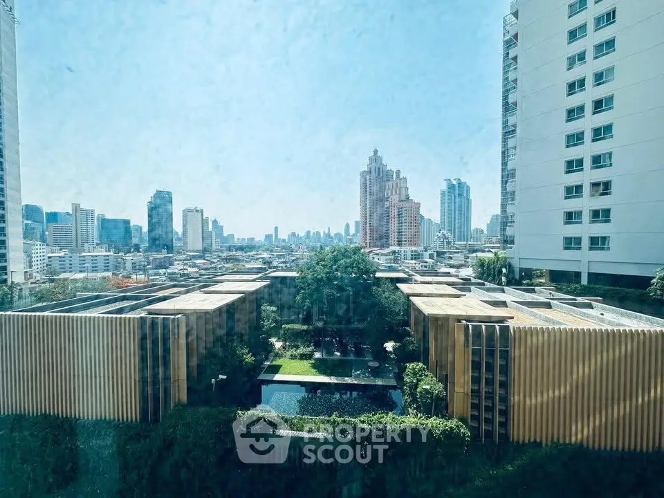 Stunning cityscape view from a high-rise building with lush garden and modern architecture.