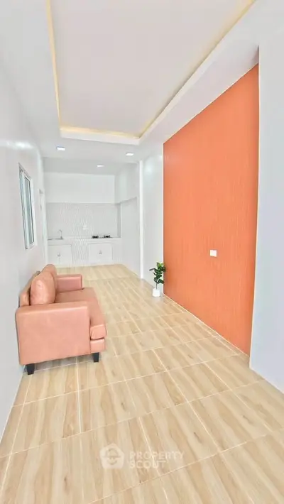 Modern living room with stylish sofa and open kitchen layout, featuring elegant wood flooring and accent wall.