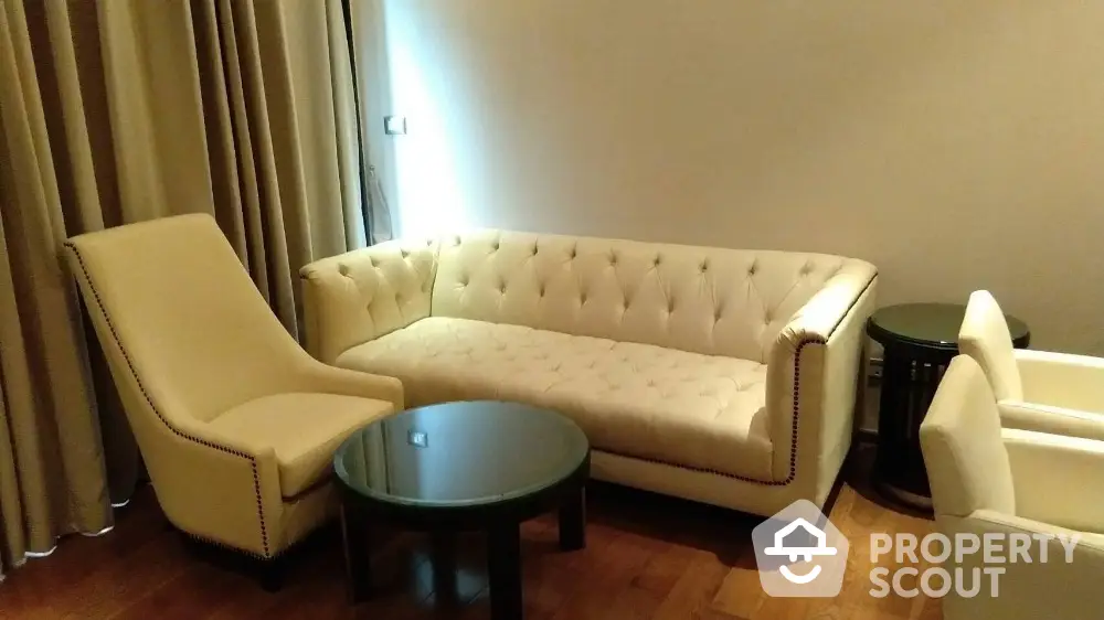 Elegant living room with plush white sofa and armchairs, complemented by a sleek round coffee table.