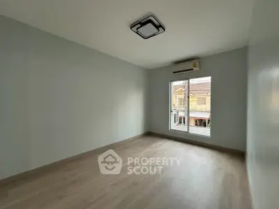 Spacious empty room with large window and modern ceiling light, perfect for customization.