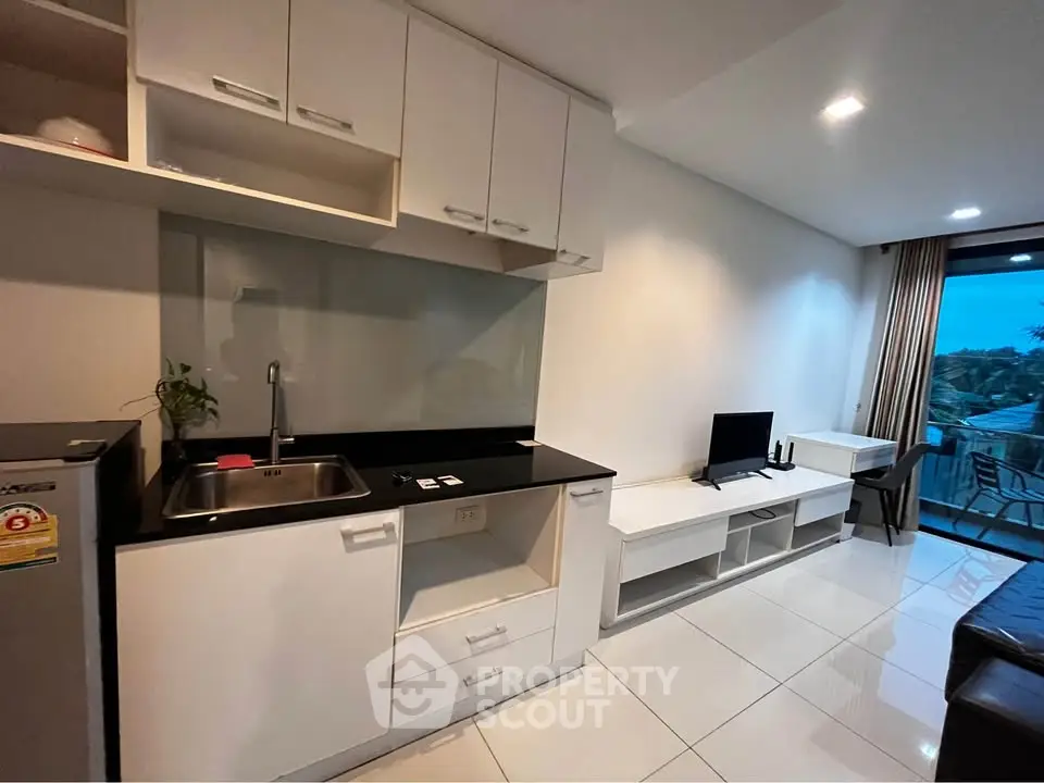 Modern studio apartment with sleek kitchen and cozy living area, featuring large windows and stylish furnishings.