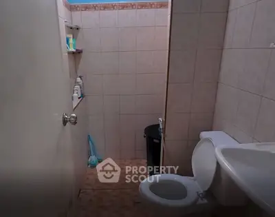 Compact bathroom with tiled walls and essential fixtures, ideal for small spaces.