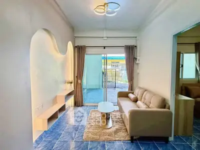 Modern living room with stylish decor and blue tile flooring, featuring a cozy sofa and sliding glass doors to a patio.
