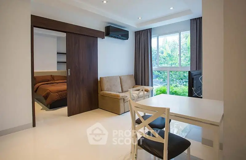 Modern living room with sliding door to cozy bedroom and garden view.