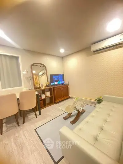 Cozy living room with modern decor, featuring a sleek sofa, dining area, and wall-mounted air conditioning.