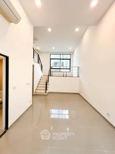 Spacious modern living room with high ceilings and sleek staircase in a contemporary home.