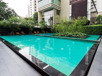 Luxurious modern apartment complex with a stunning outdoor pool and lush greenery.