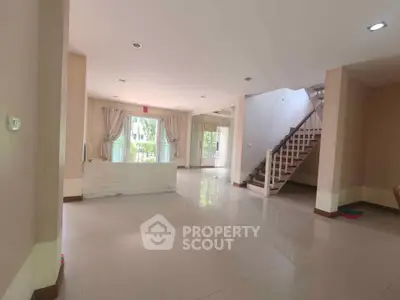 Spacious open-plan living area with large windows and staircase, perfect for modern family living.