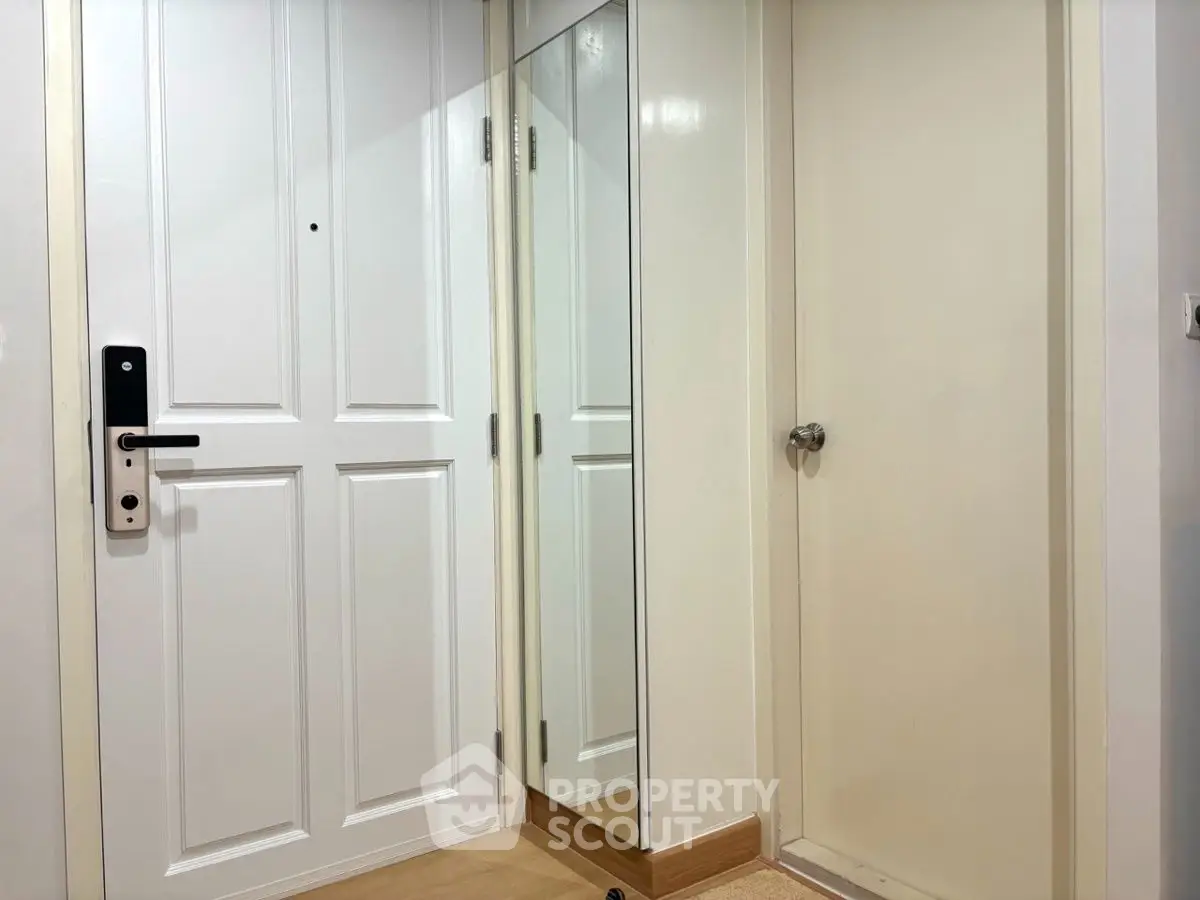 Modern apartment entrance with white door and full-length mirror