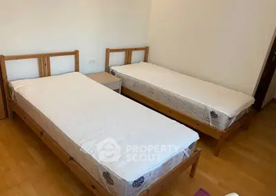 Spacious bedroom with twin beds and wooden flooring, ideal for comfortable living.