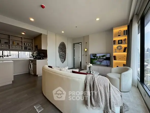 Modern living room with open kitchen and city view, featuring elegant decor and cozy seating.