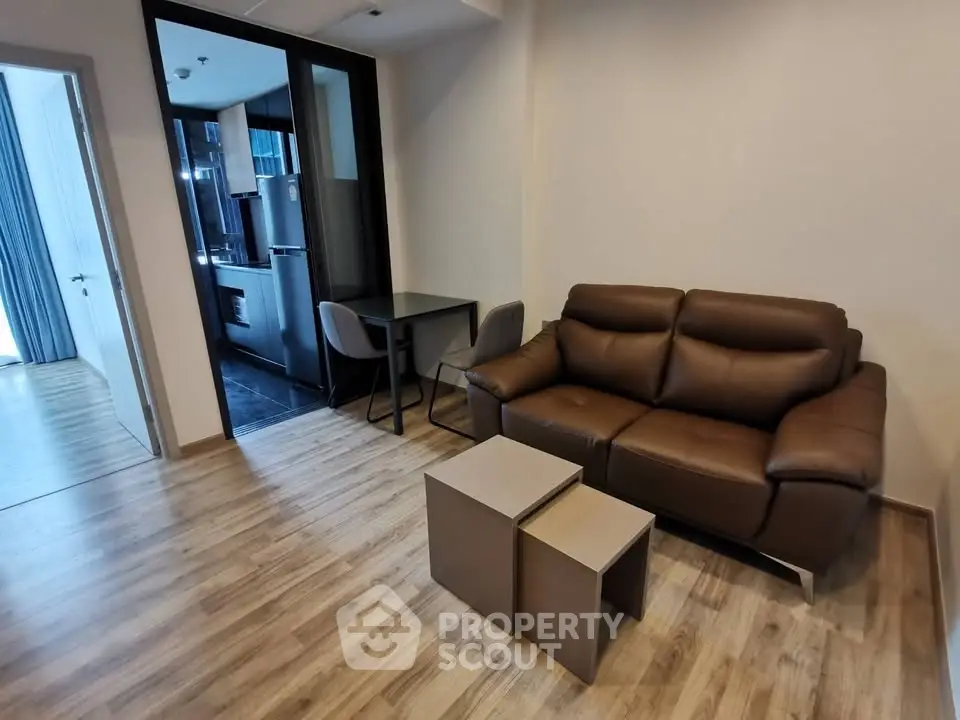 Modern living room with brown leather sofa and compact dining area in stylish apartment.