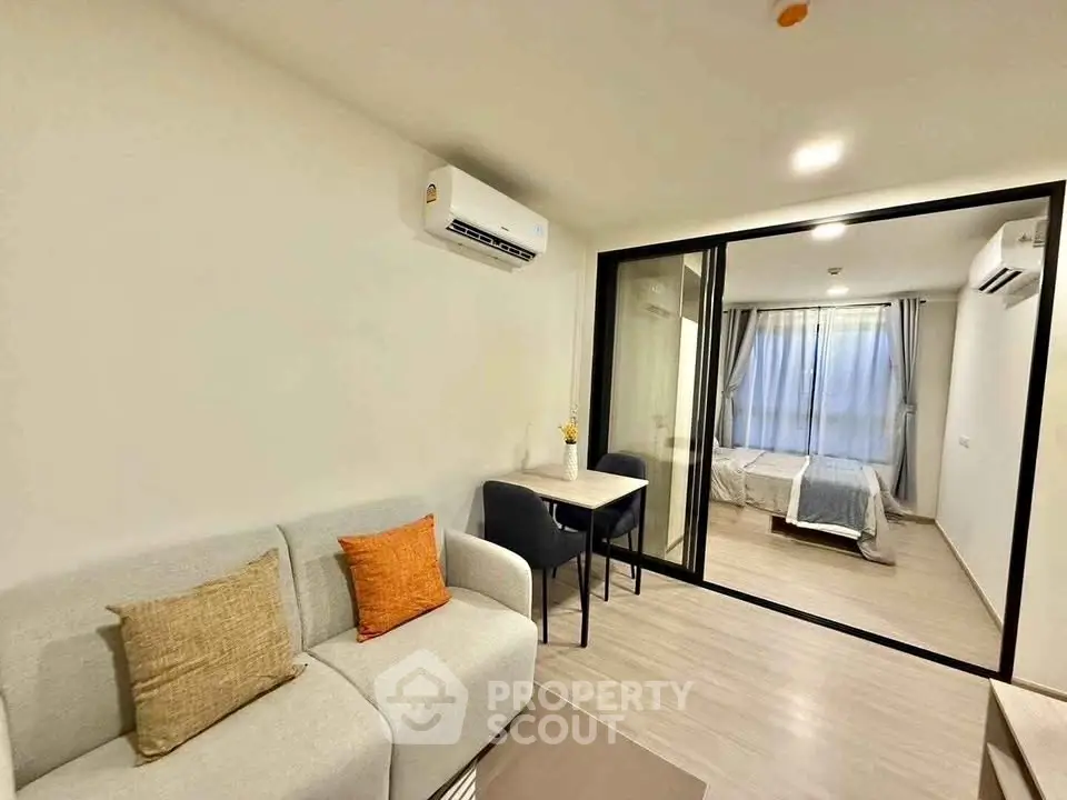 Modern living room with cozy sofa and dining area leading to a stylish bedroom.