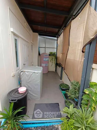 Charming outdoor utility area with plants and covered appliances