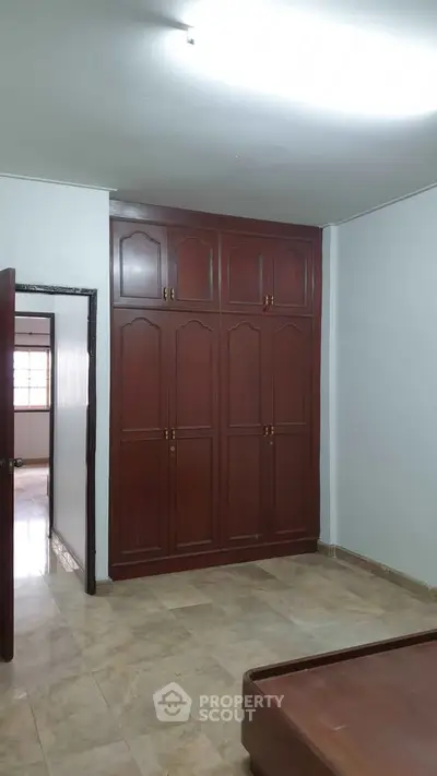 Spacious bedroom with built-in wooden wardrobe and marble flooring