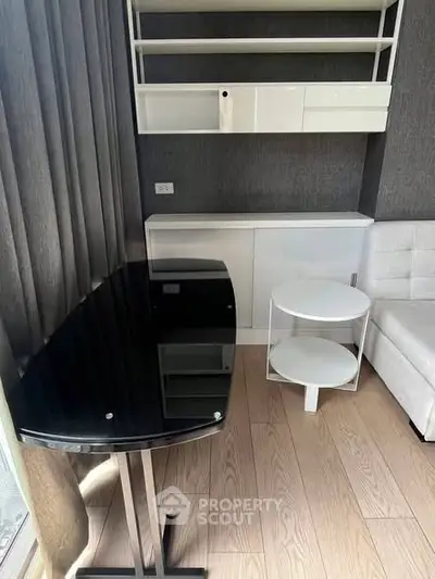 Modern living room with sleek black glass table and white shelving unit.