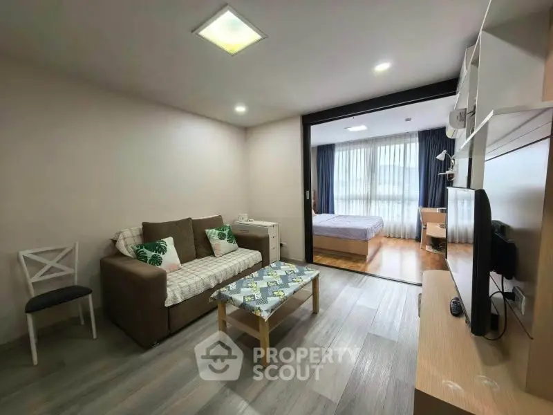 Modern open-plan living room with cozy sofa and bedroom view, perfect for urban living.