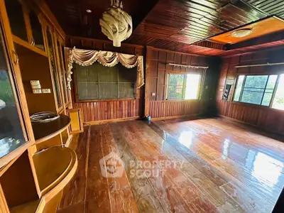 Spacious wooden living room with large windows and unique ceiling light fixture