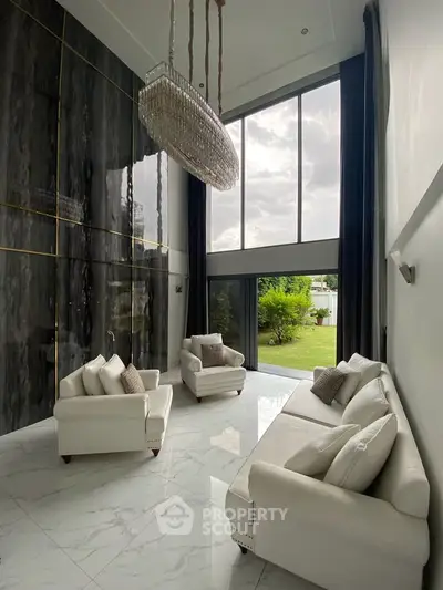 Luxurious high-ceiling living room with elegant chandelier and garden view