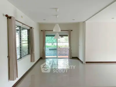 Spacious empty living room with large windows and sliding glass doors to balcony.