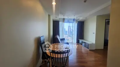 Spacious living room with city view, wooden flooring, and modern furniture in a high-rise apartment.