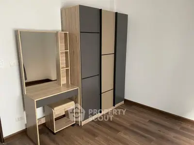 Modern bedroom with sleek wardrobe and stylish vanity set on wooden flooring.