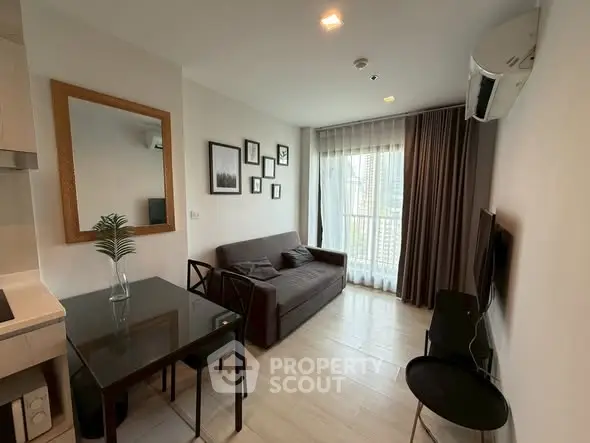 Modern living room with sleek furniture and large window offering city views.