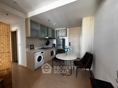 Modern compact kitchen with washing machine and dining area in stylish apartment.