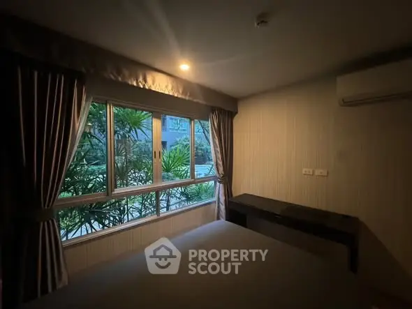 Cozy bedroom with large window and garden view, featuring elegant curtains and air conditioning.