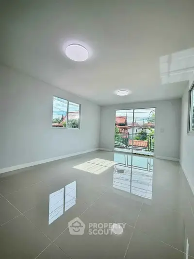 Spacious empty room with glossy tiled floor and large windows offering natural light.