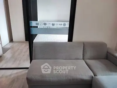Modern apartment interior with cozy sofa and bedroom view through glass partition.