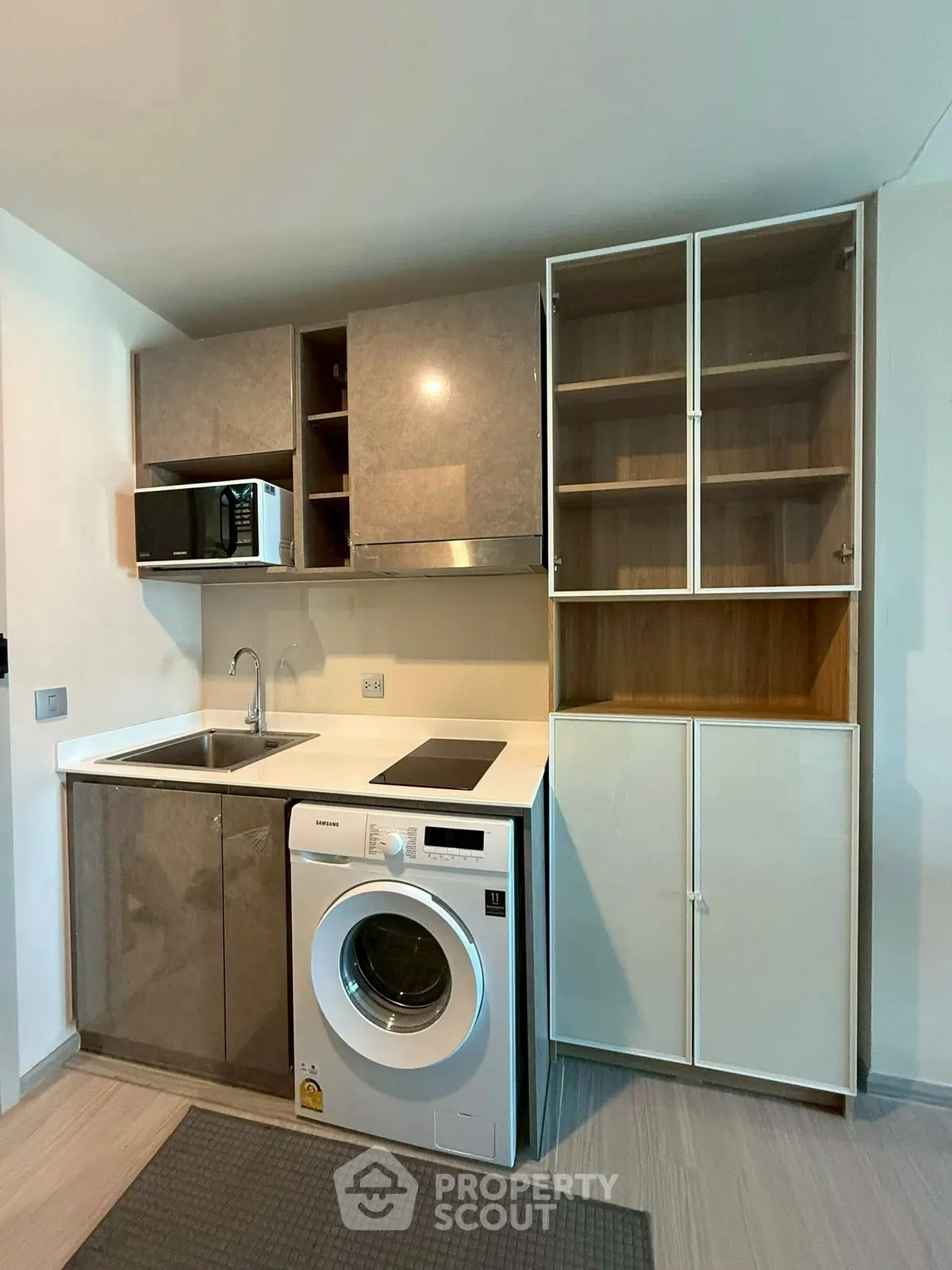 Modern compact kitchen with washing machine and microwave, sleek cabinets, and efficient layout.