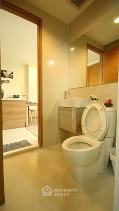 Modern bathroom with sleek fixtures and open doorway to adjacent room.