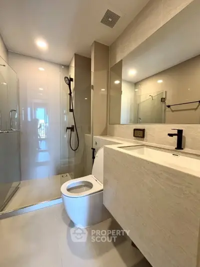 Modern bathroom with glass shower and sleek fixtures in luxury apartment.
