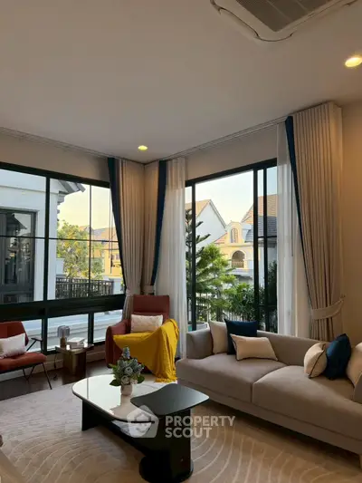 Elegant living room with large windows and stylish furniture, offering a cozy and inviting atmosphere.