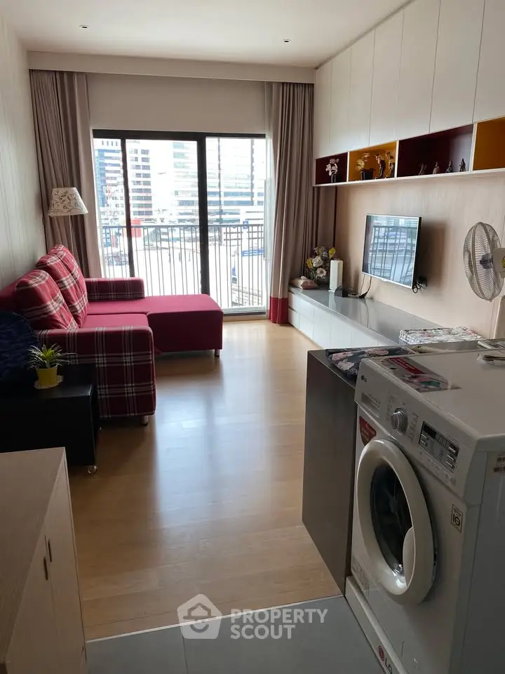 Modern living room with balcony view, featuring stylish furniture and in-unit washing machine.
