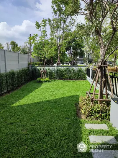 Spacious green garden with lush lawn and trees in a serene residential area.