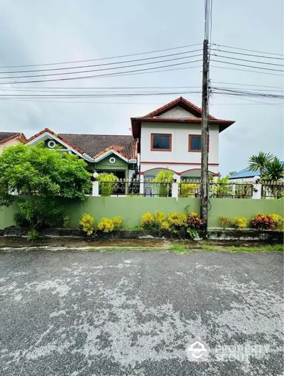 Charming two-story house with lush garden and secure fence in a serene neighborhood.