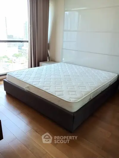 Spacious bedroom with large window and modern bed in urban apartment