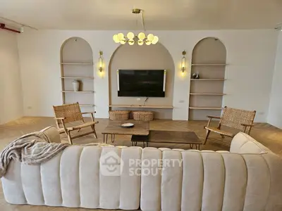 Elegant living room with modern decor and built-in shelves, featuring a cozy sofa and stylish lighting.