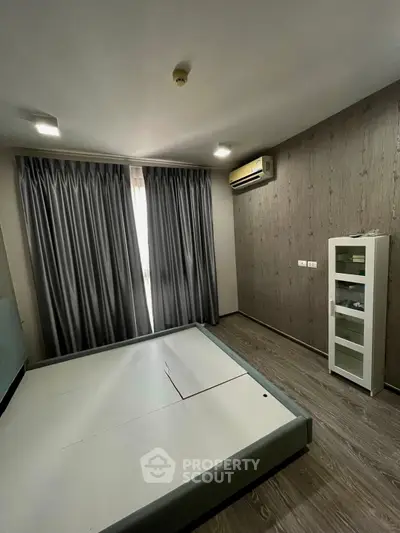 Spacious bedroom with modern design and air conditioning, featuring elegant curtains and sleek flooring.