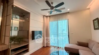 Modern living room with ceiling fan, sleek TV setup, and floor-to-ceiling windows offering city views.