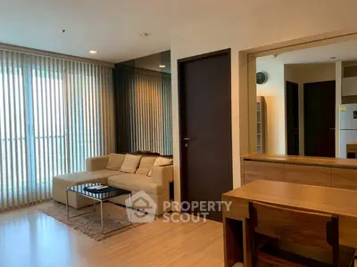 Modern living room with cozy beige sofa and large windows with vertical blinds.