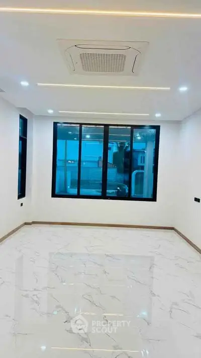Spacious modern room with large windows and marble flooring, perfect for a bright living space.